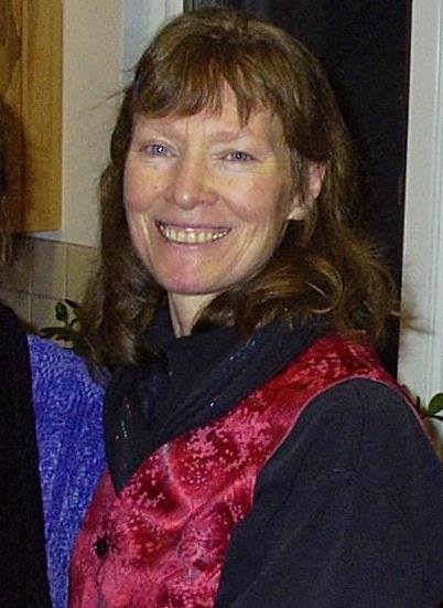 two smiling women are standing together and one is wearing a vest