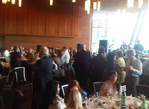 many people are gathered at tables near a large window