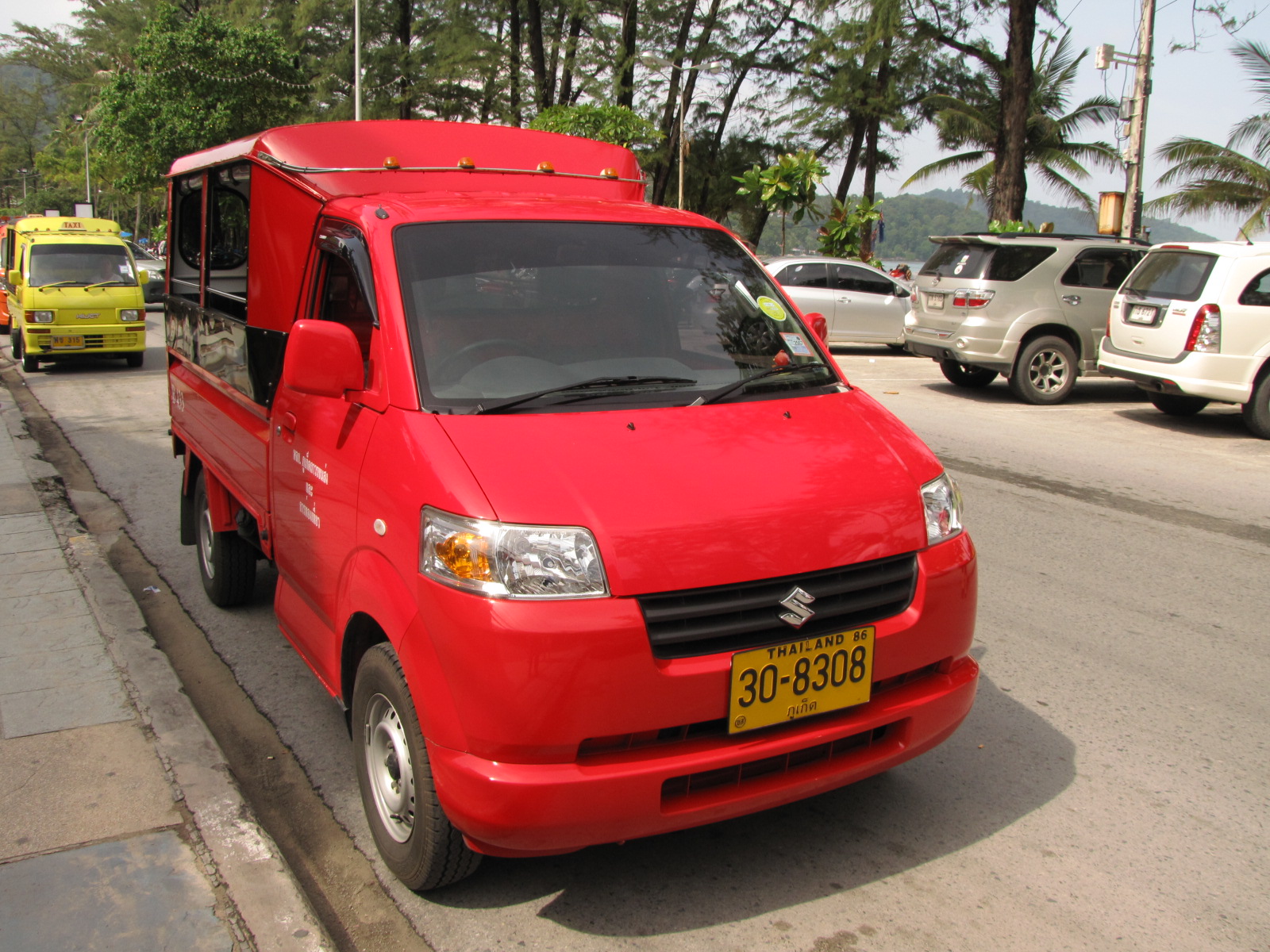 red truck and van parked on street near a curb