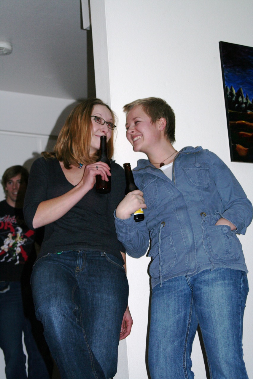 two people standing near a wall and drinking