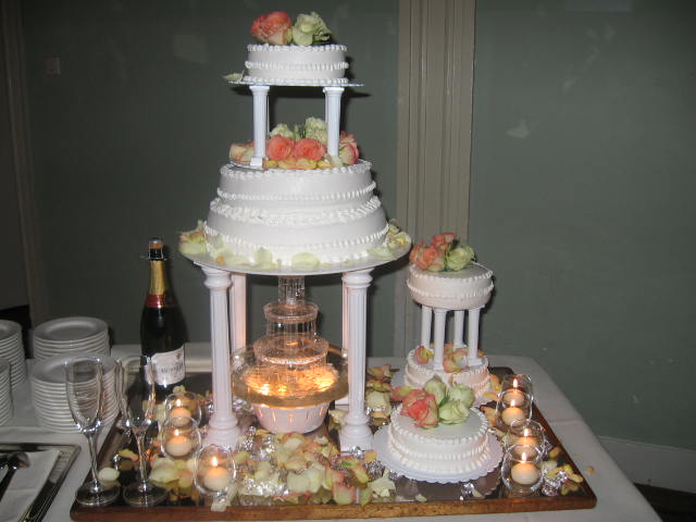 a triple tiered wedding cake on display in front of some wine glasses