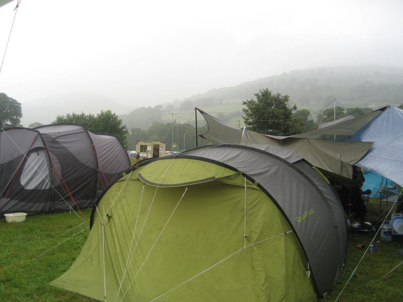 large green tent on grassy field with mountains in the background