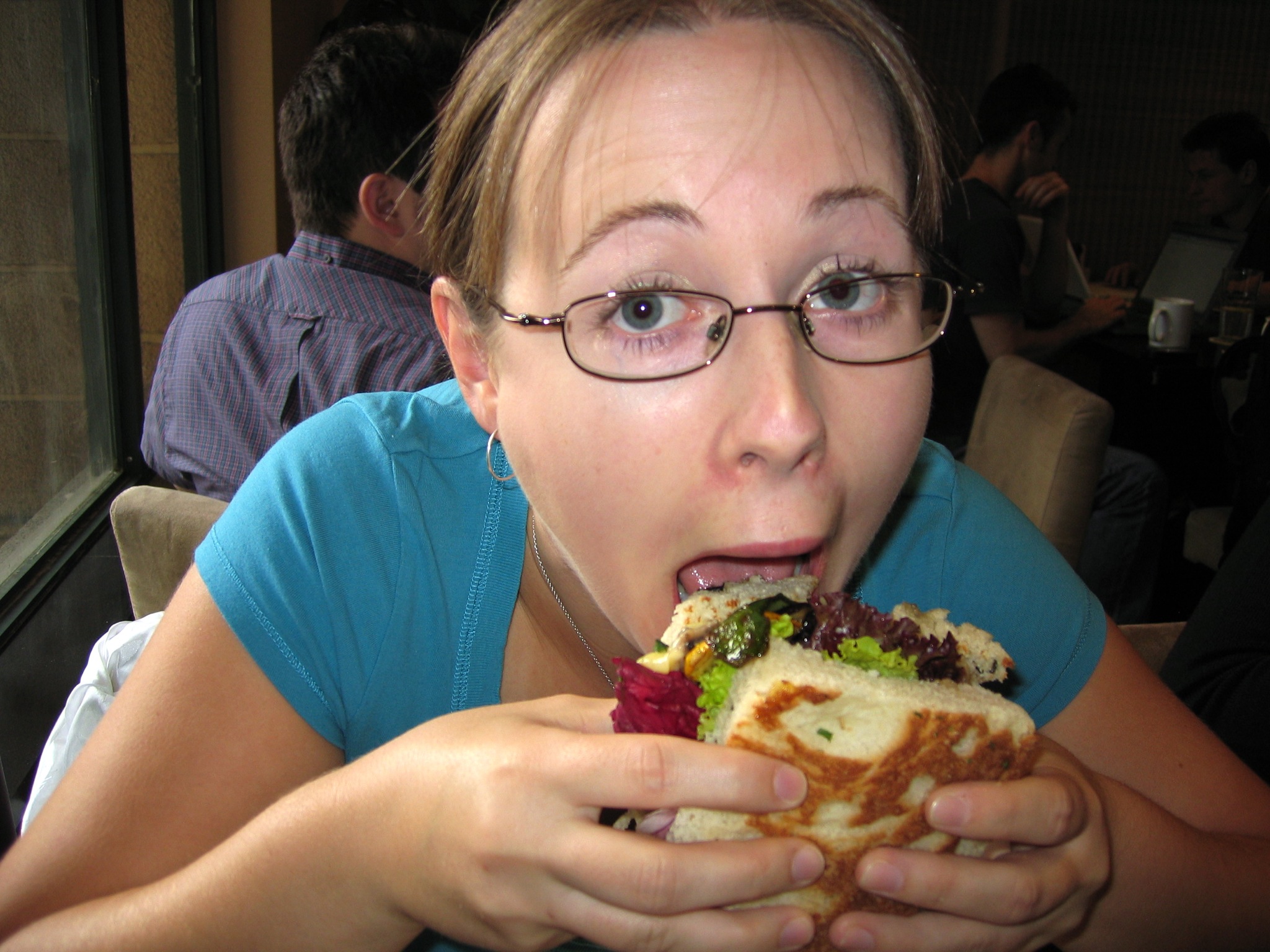 a young woman is biting into a sandwich