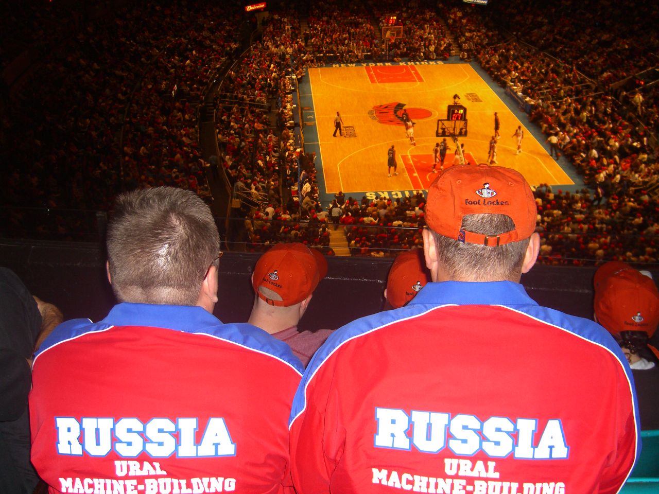 two men with red hats are sitting in the stands at a stadium