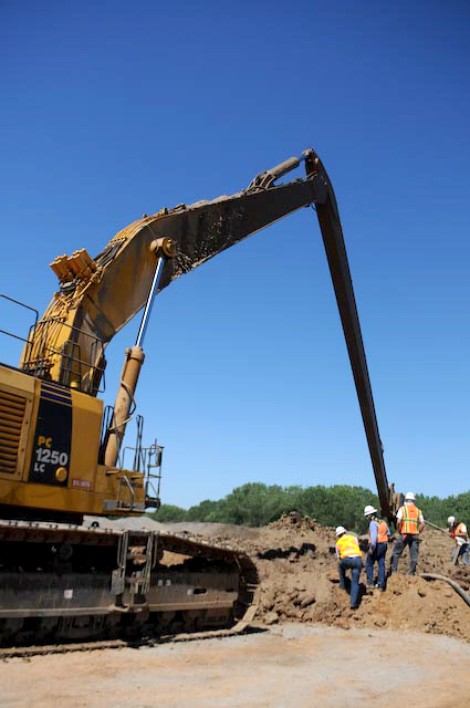 construction workers work together as they stand around a large bulldozer
