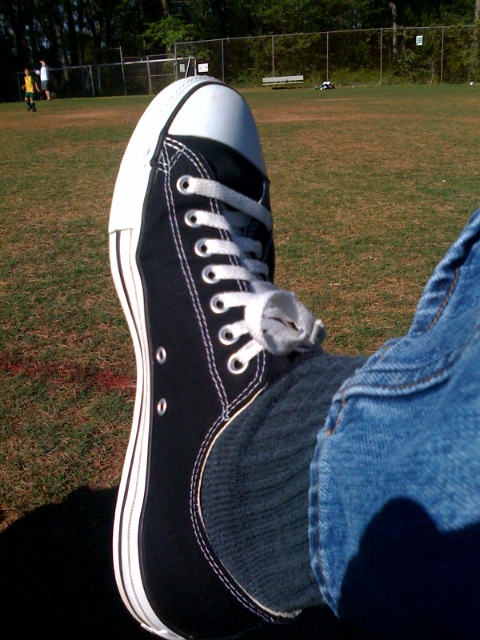 a person wearing converse tennis shoes in a grassy area