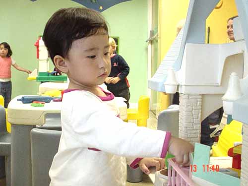 a  playing with the back of a wooden dollhouse