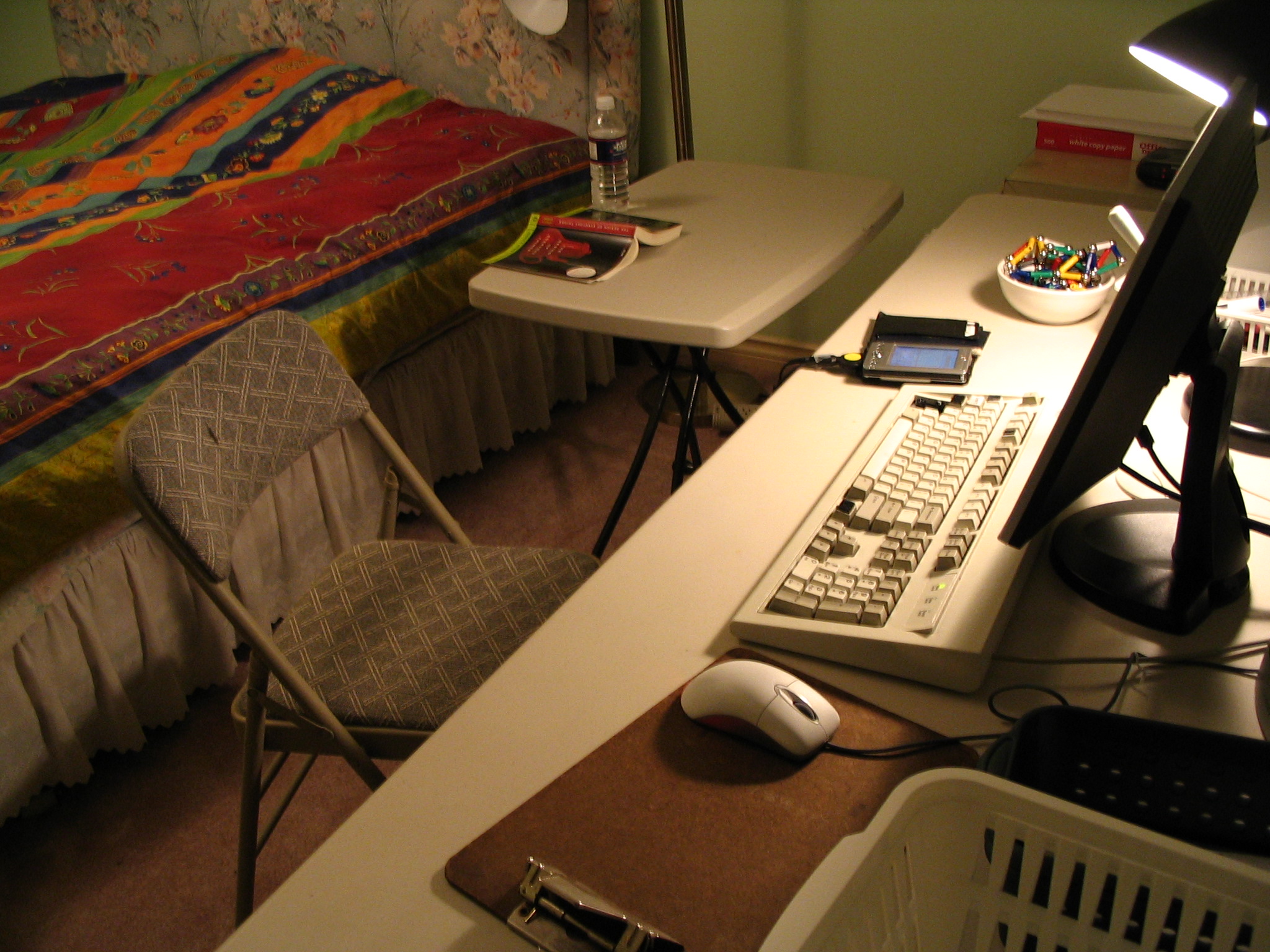 an old computer sitting on top of a desk next to a bed