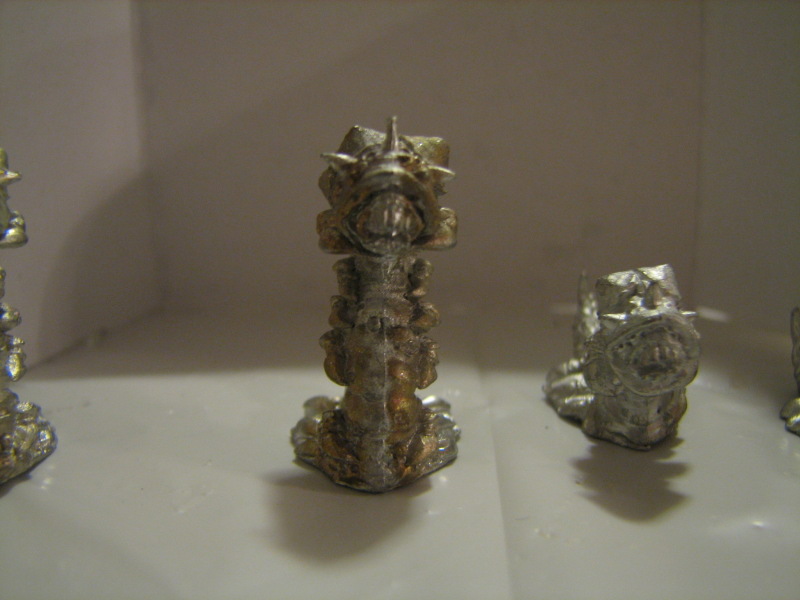three silver objects on display in a white space