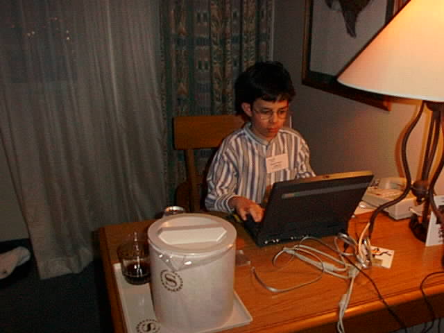 a little boy is sitting at a desk with his laptop