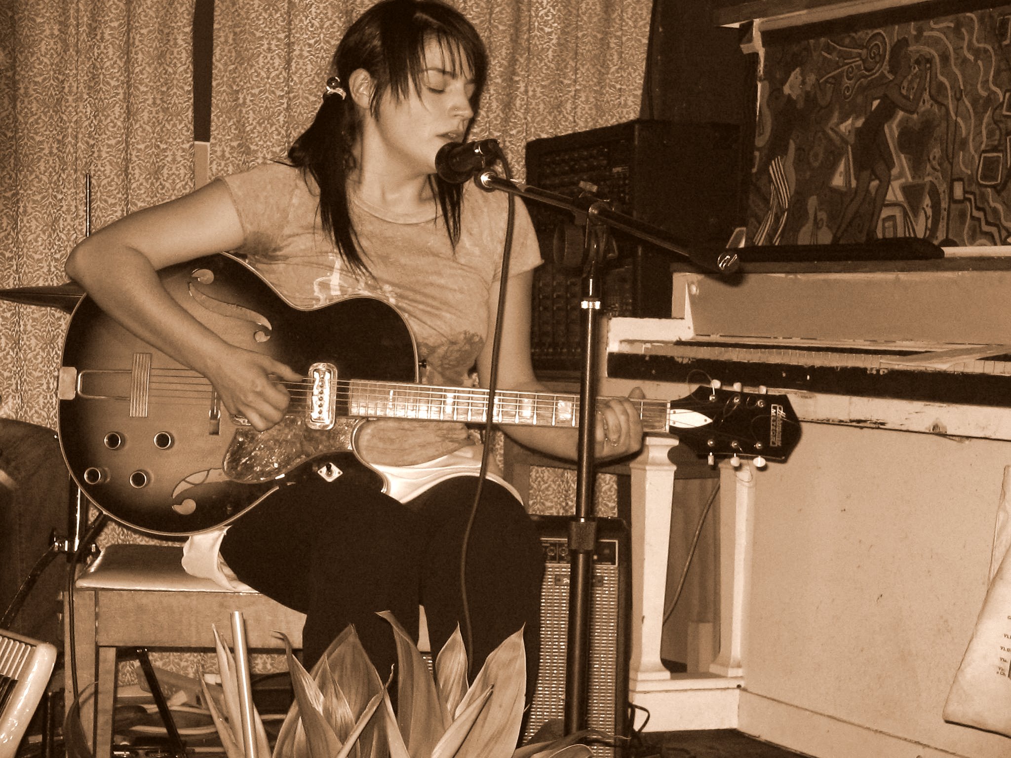 a girl sitting at a piano and playing a guitar