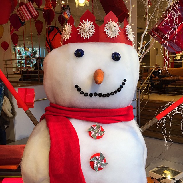 a snowman with a red scarf and tiara on top