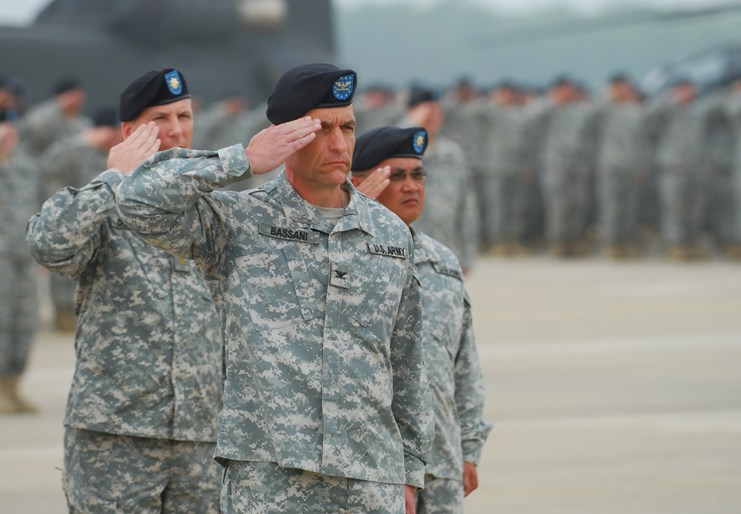 two soldiers saluting while other soldiers salute