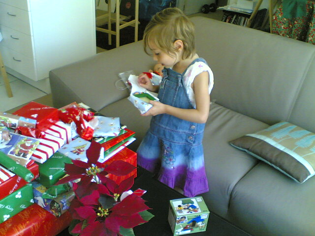 a little girl with a lot of gifts sitting next to a couch