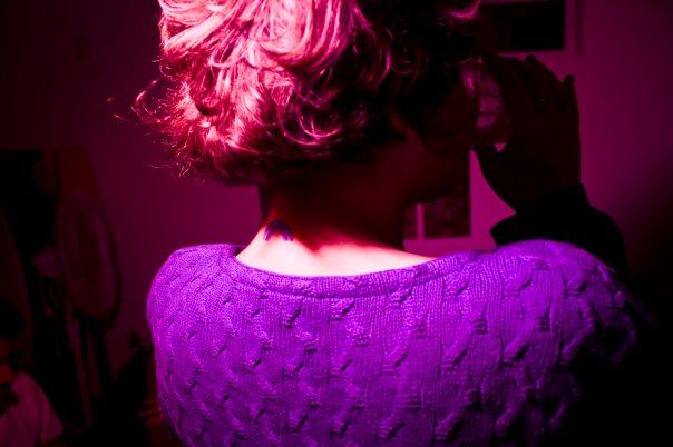 a woman's back view in the dark, with pink and purple lighting