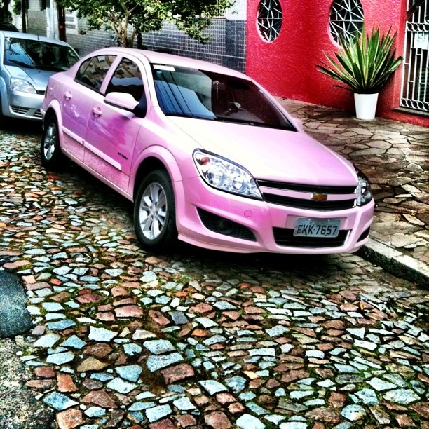 a pink car parked on the street next to a red building