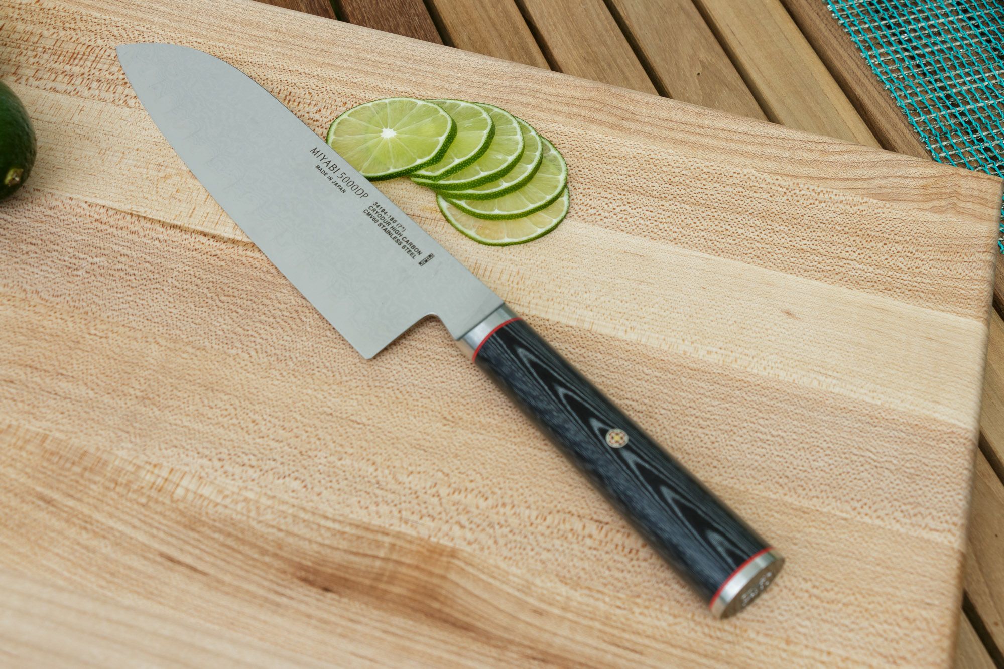 a knife and limes sitting on a  board