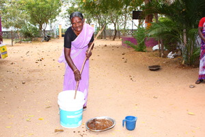 an indian woman standing next to a plastic bucket