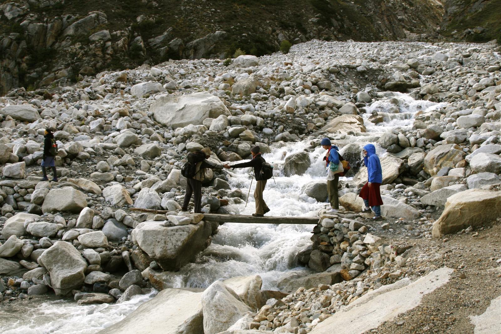 four people are climbing on a rock and water obstacle