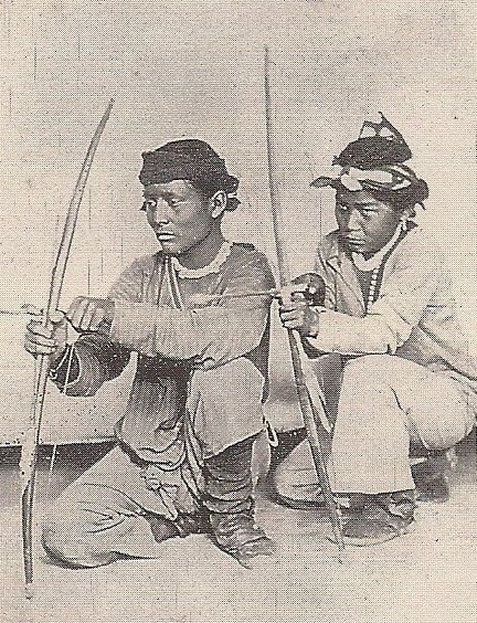 two indian men are sitting on the ground and holding their arrows