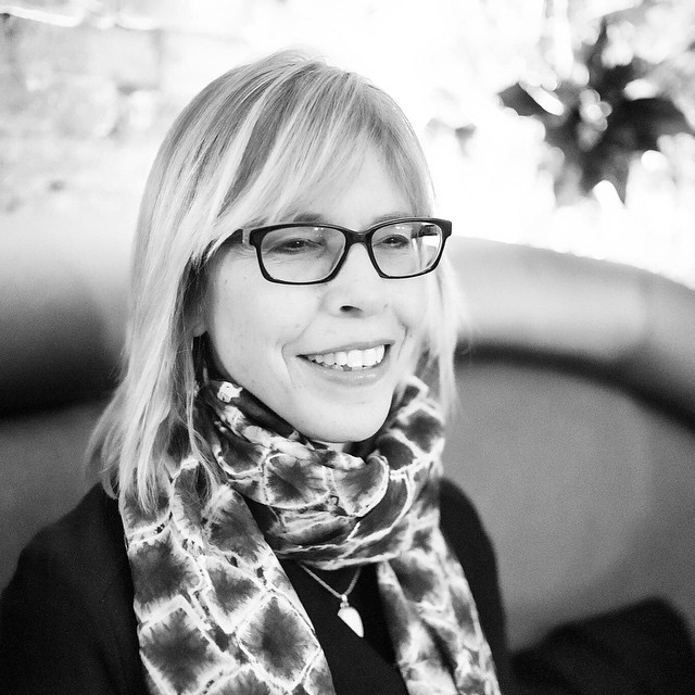 a woman wearing glasses and a scarf smiling
