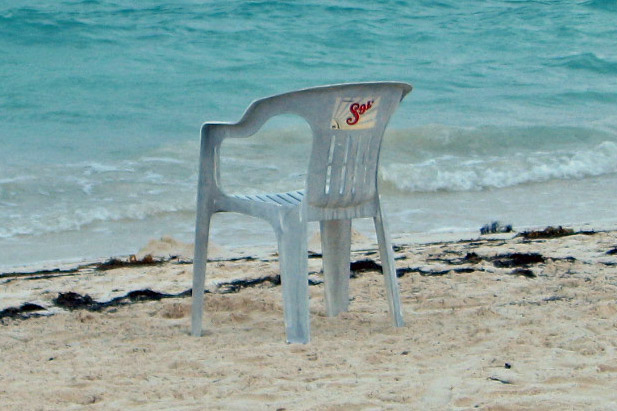 a plastic chair sitting on top of a beach