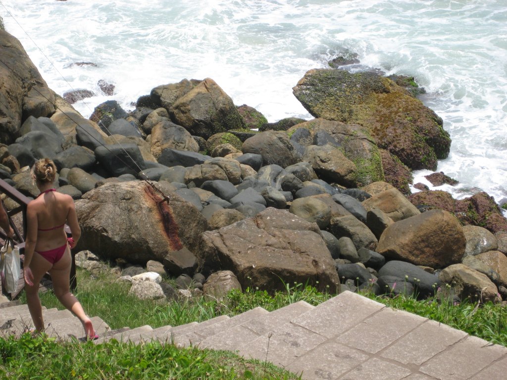 a young lady in a bikini walking up stairs to the beach