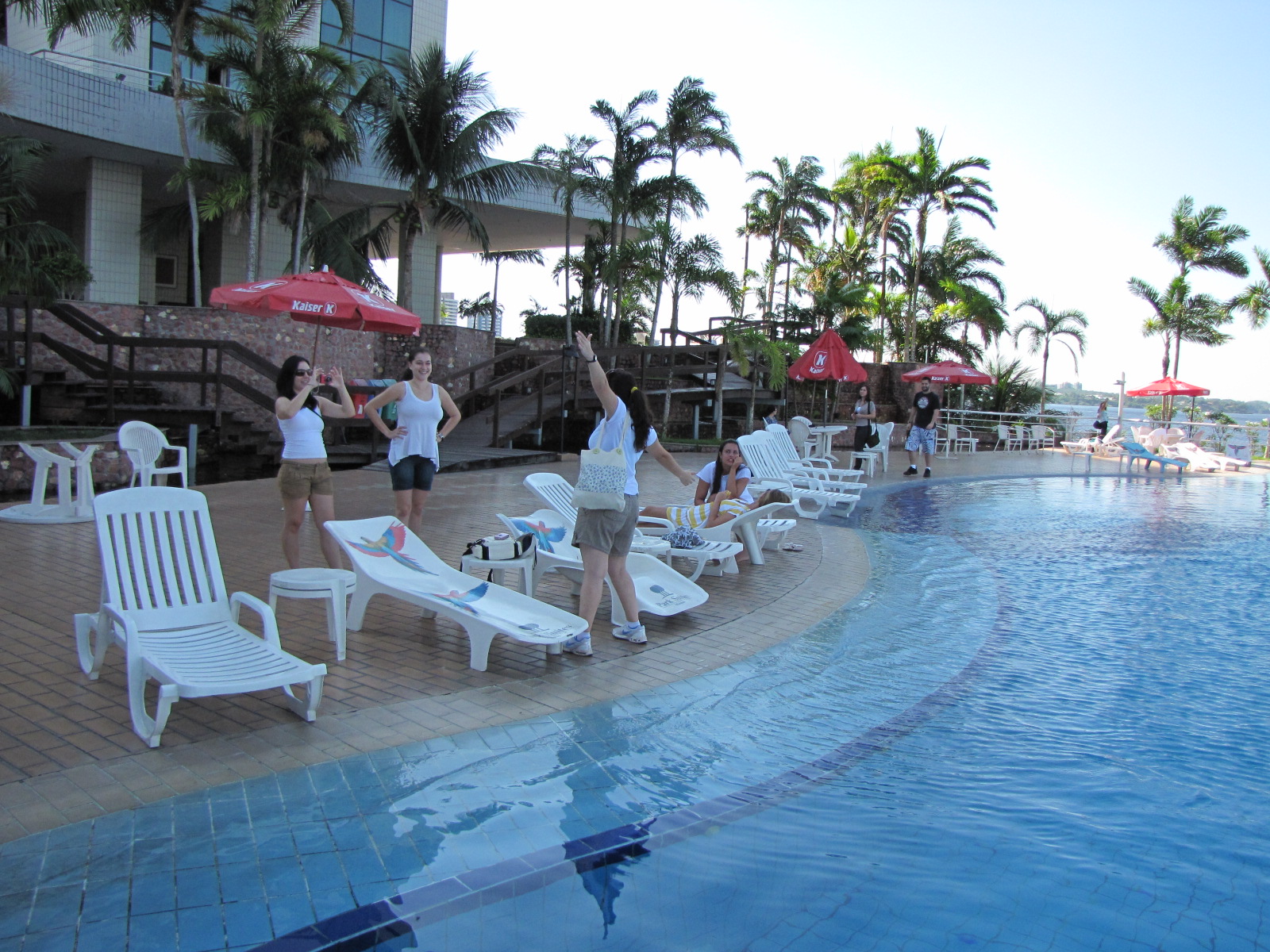 people are relaxing in lounge chairs beside a pool