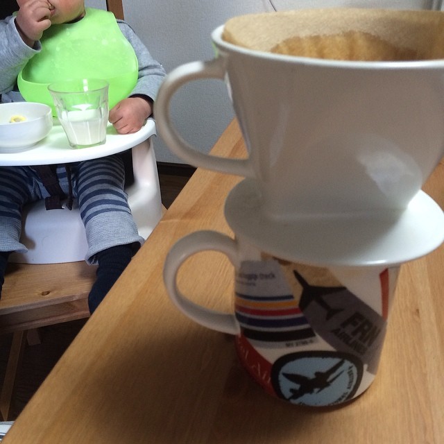 a child eating food from a highchair next to a coffee mug and plate