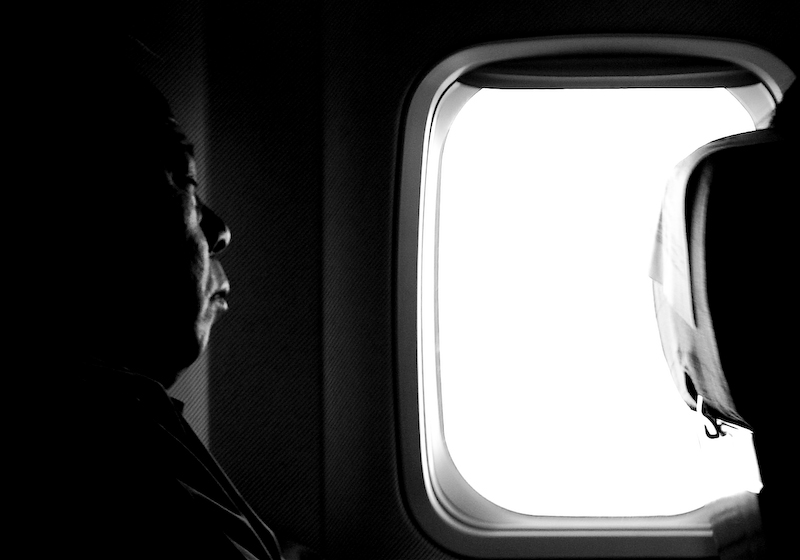 the man is standing by the window of his airplane