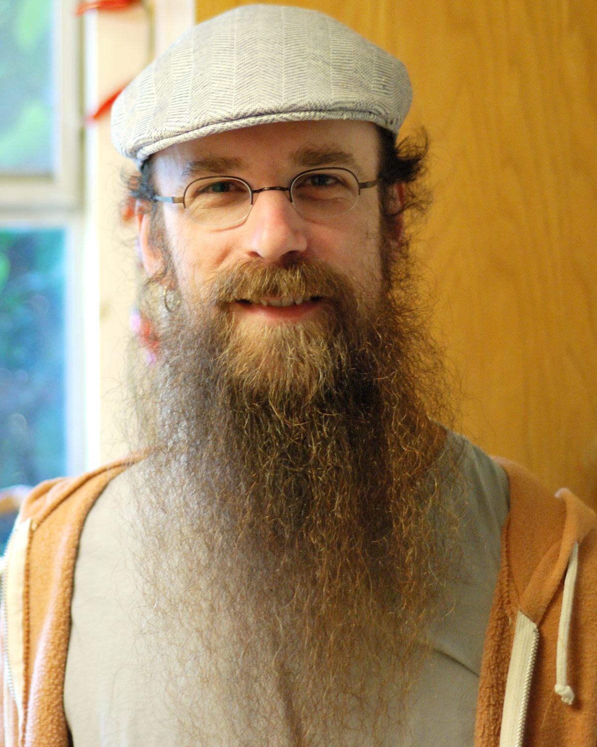 a bearded man with glasses and a cap on