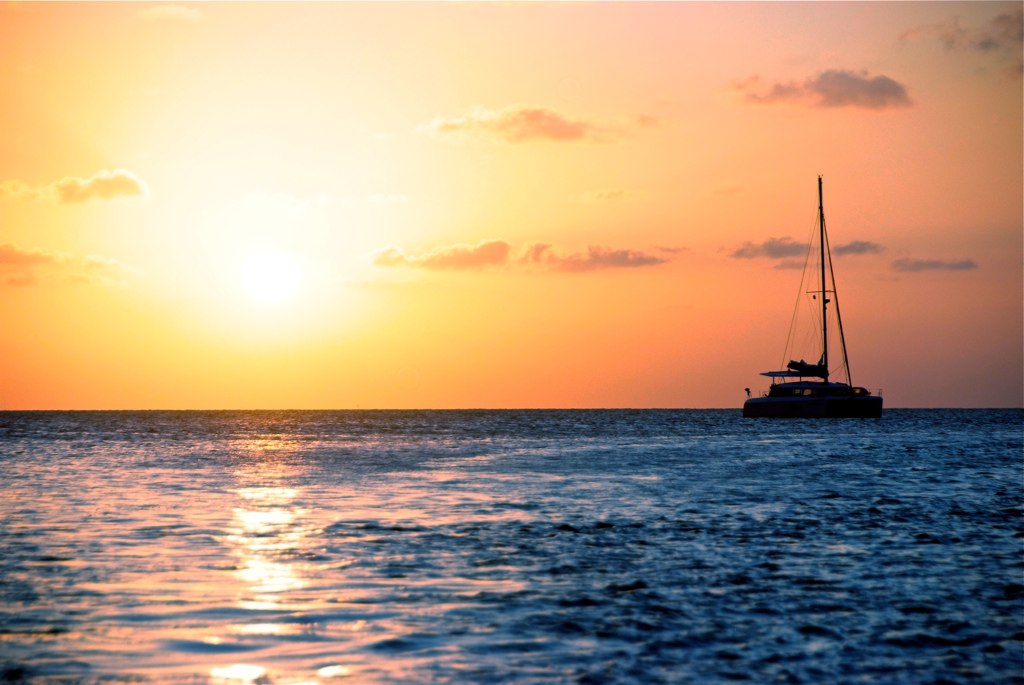 a boat is sailing out at sea at sunset