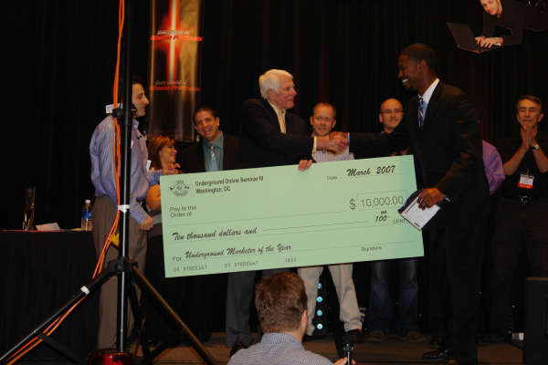 a man standing next to a giant check in front of a crowd