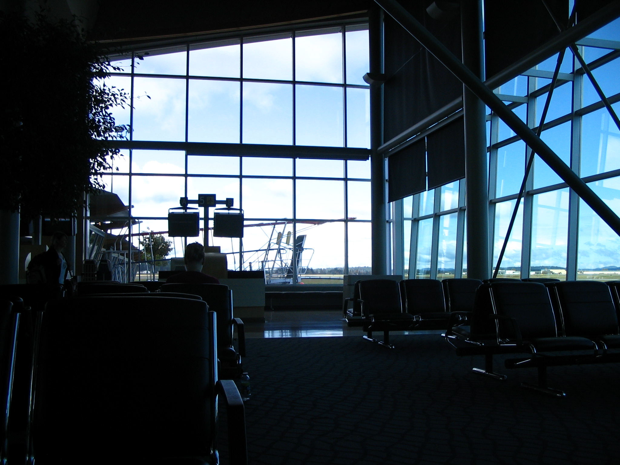 an empty airport lounge area with chairs and lots of windows