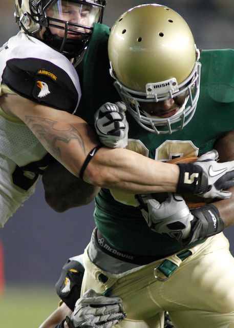 a man wearing a football uniform being tackled by another man in green and white