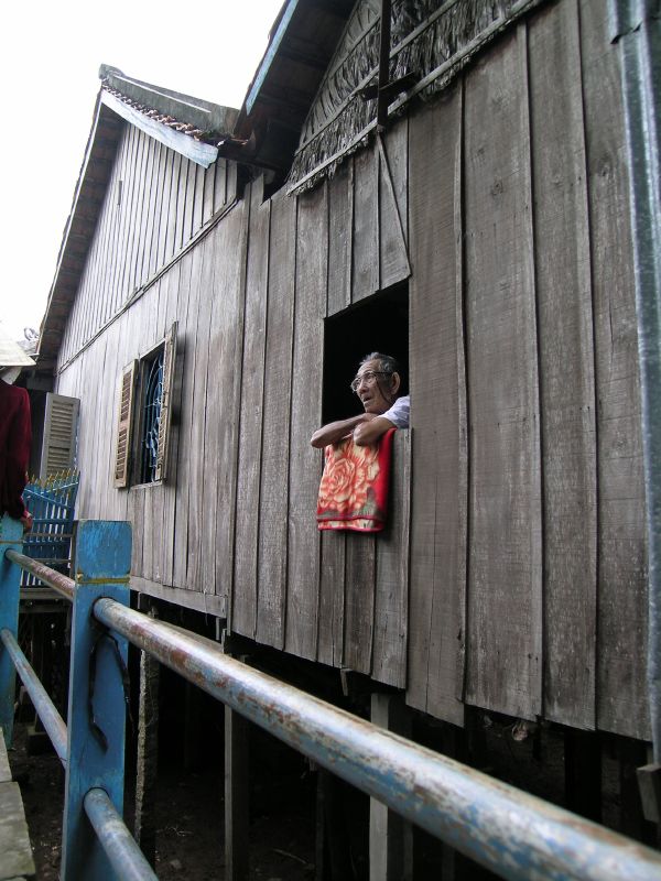 a man on a porch looks out at the sky from behind a wooden house