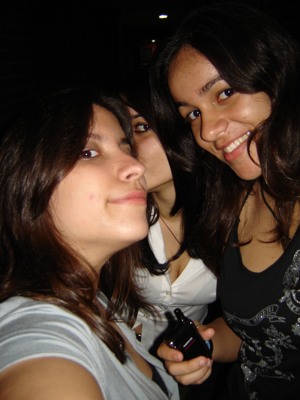 three smiling girls pose for a picture in the dark