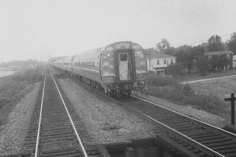 the passenger train is driving along the track in the fog