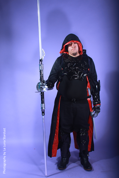 man dressed in black and red outfit, holding long sword
