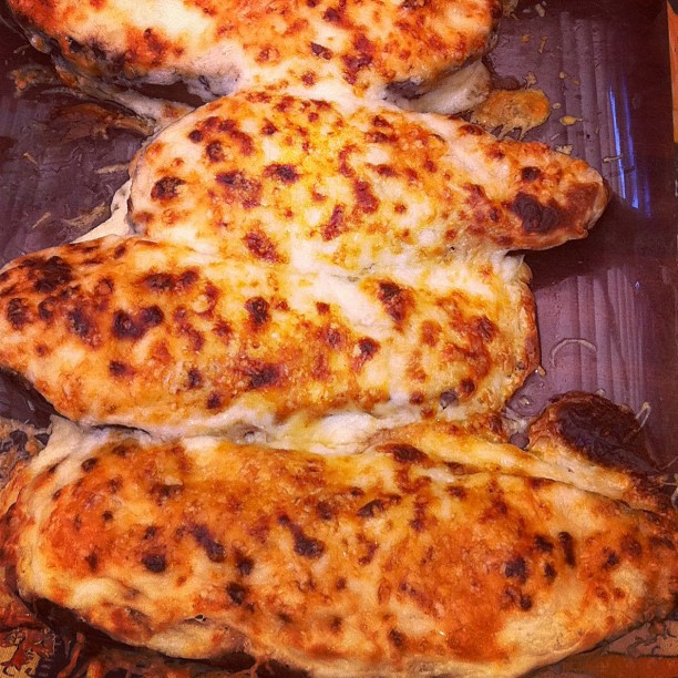 three homemade cheese covered pizzas in a cardboard box
