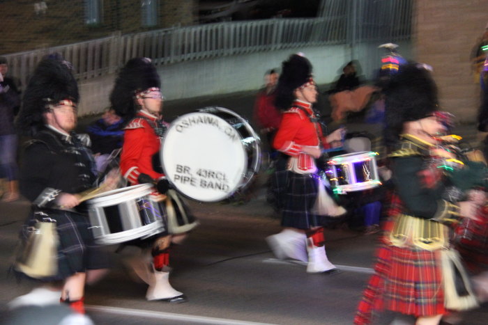 several people in tartan attire carry marching instruments