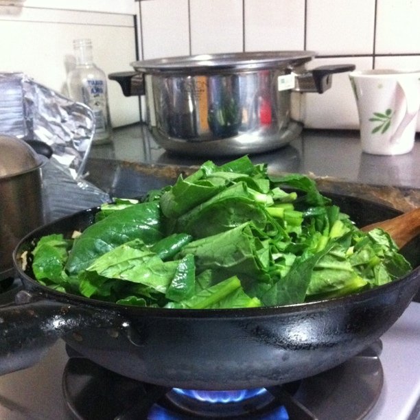 there is a large pan filled with spinach on the stove