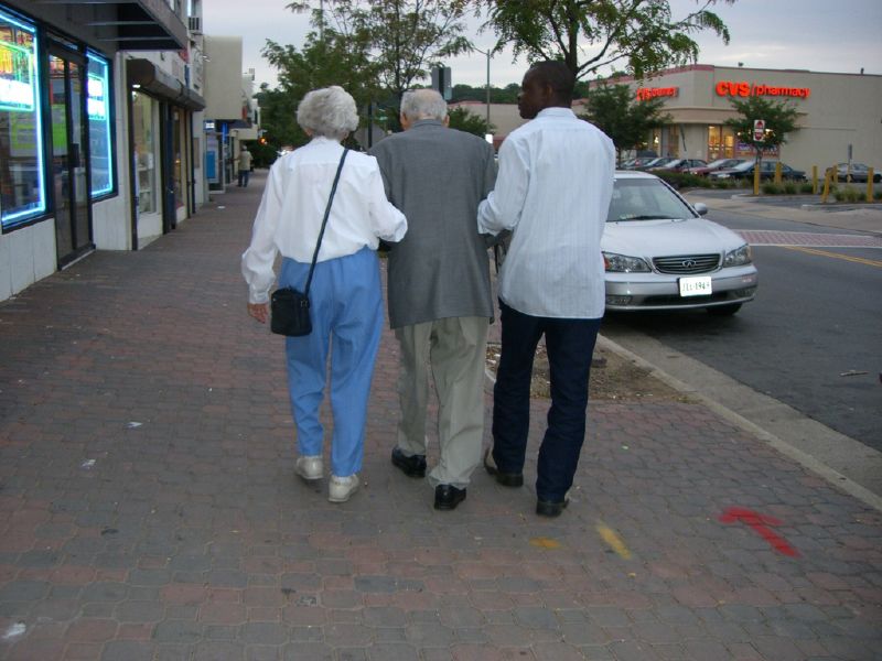 two elderly people are walking down the street