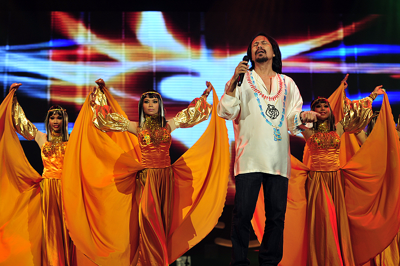 a man stands among two woman who are singing