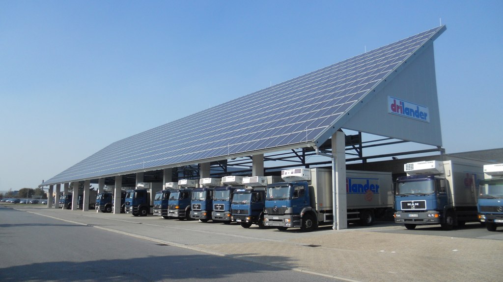 several trucks and buses are parked outside a solar power station