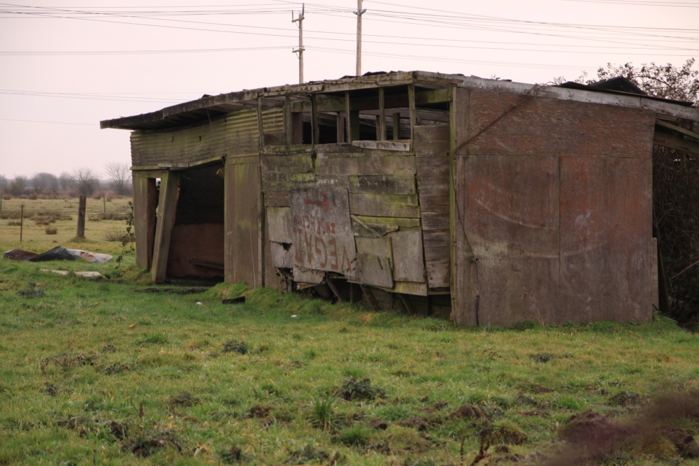 a wooden shack with a few windows and broken doors