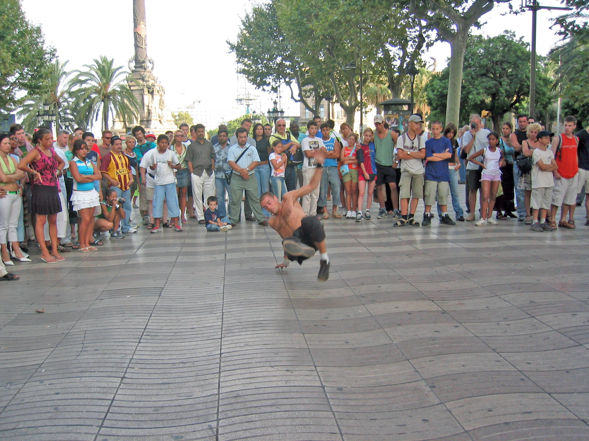 a man on a skateboard rides in the street as a crowd watches