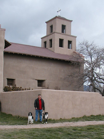 a man standing with two dogs in front of an old building
