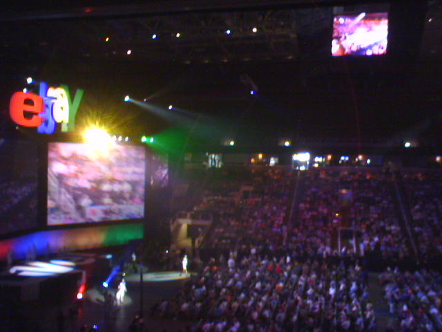 a dark arena filled with people watching a large screen