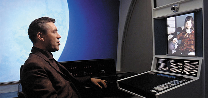 a man sitting in front of a large monitor in a room